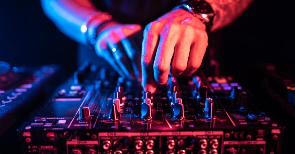 Close up of DJ hands controlling a music table in a night club.