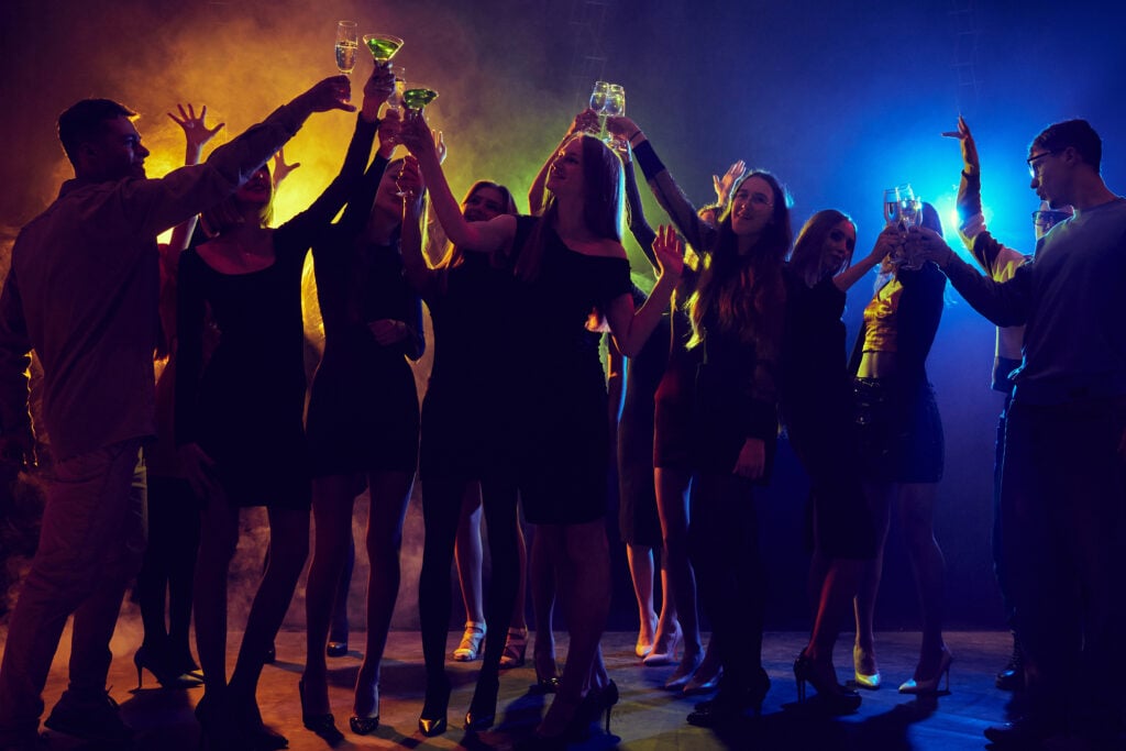 Group of young people, boys and girls, students have fun in nightclub, attending party, dancing under multicolored neon lights. Dynamic music, festive mood. Concept of youth culture, entertainment